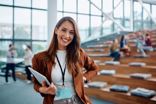 Happy female entrepreneur attending business seminar in conference hall and looking at camera. Happy businesswoman attending a conference in convention center and looking at camera. Copy space.